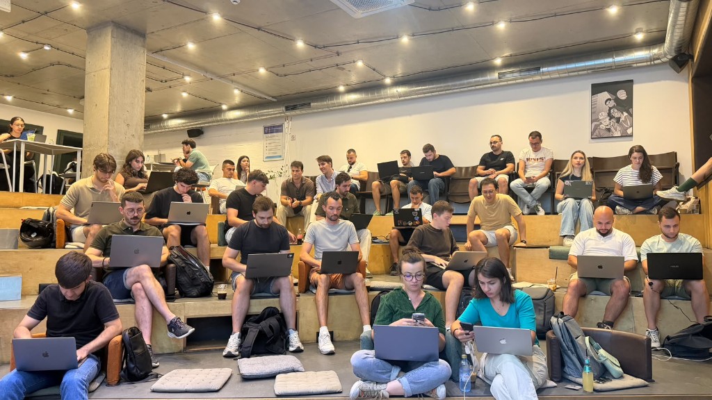 Attendees with laptops on the stepped seating at Netaville during Build with Cursor Skopje
