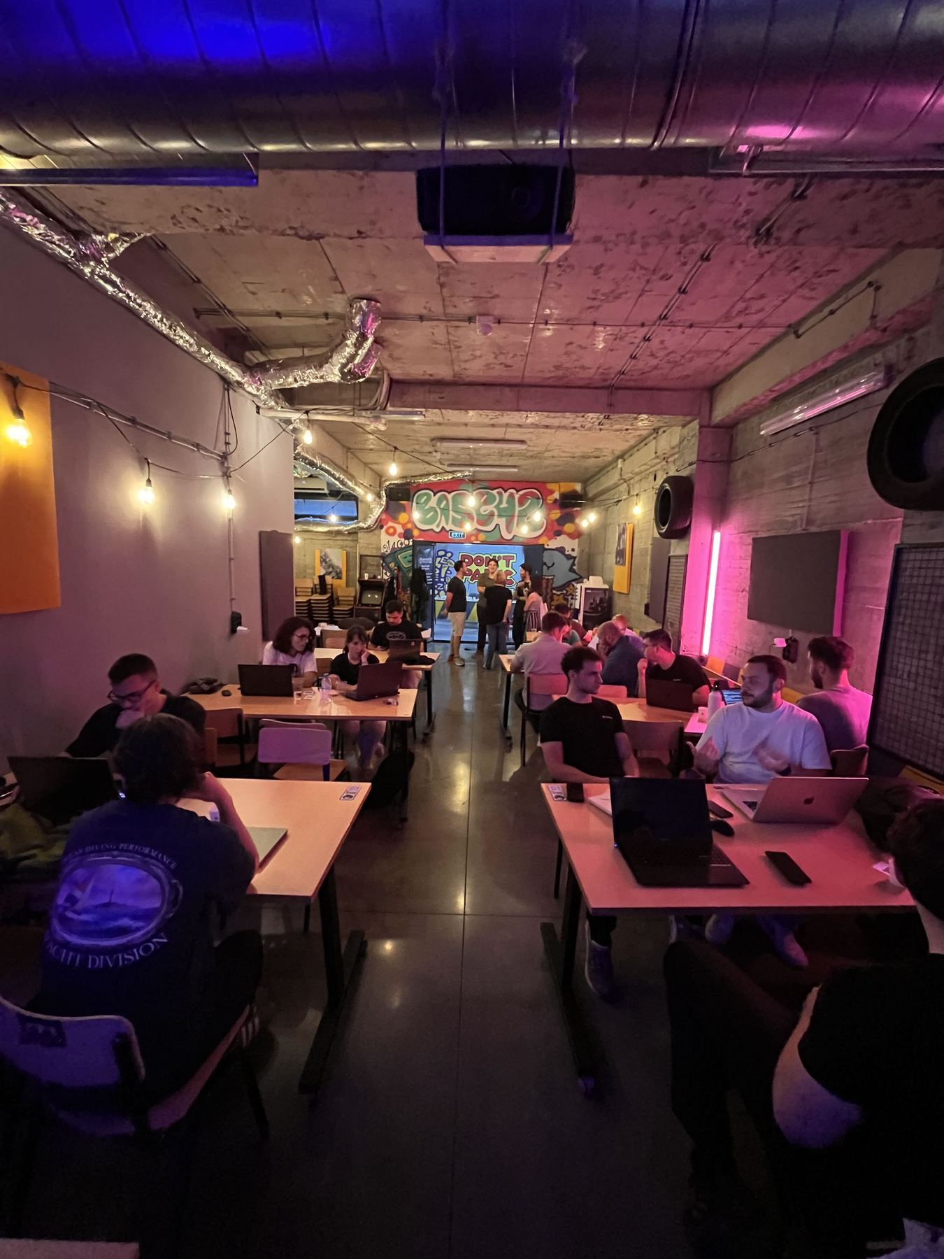 Attendees working on laptops at shared tables during the meetup